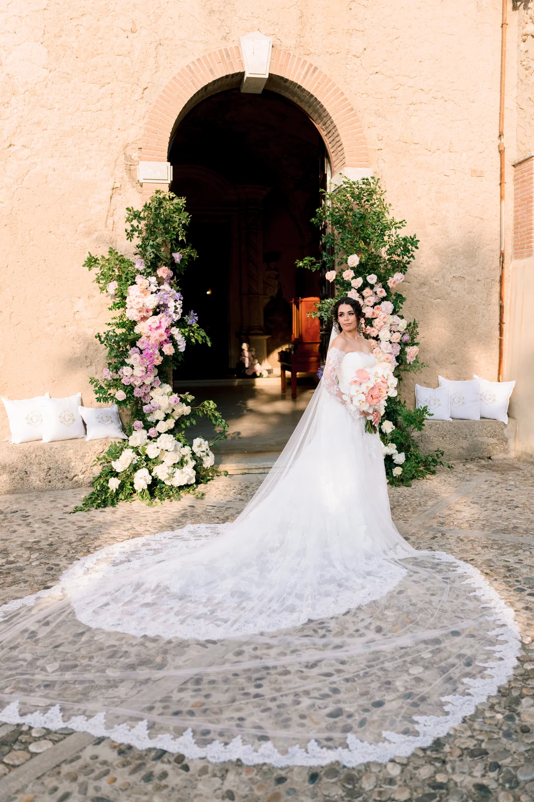 Claudia & Gianluca — la sposa e lo strascico sotto l'arco fiorito