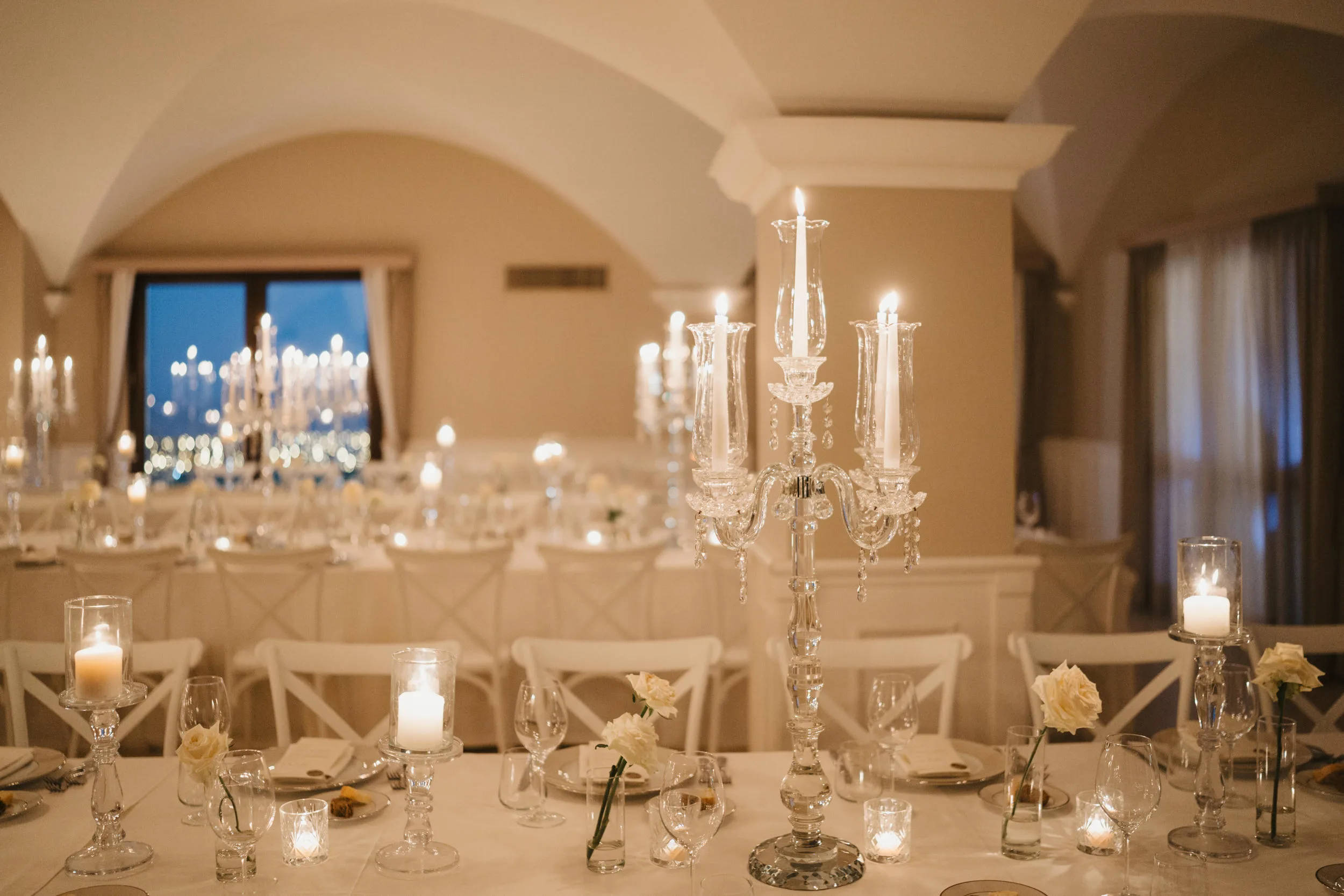 Tavola allestita con candelabri e luce calda — mise en place